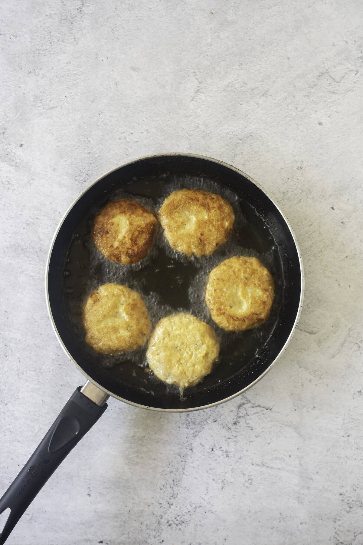 potato fritters frying in pan